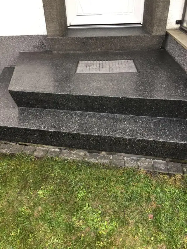 Dunkle Granitstufen im Außenbereich nach der Aufarbeitung, bereit für die Imprägnierung